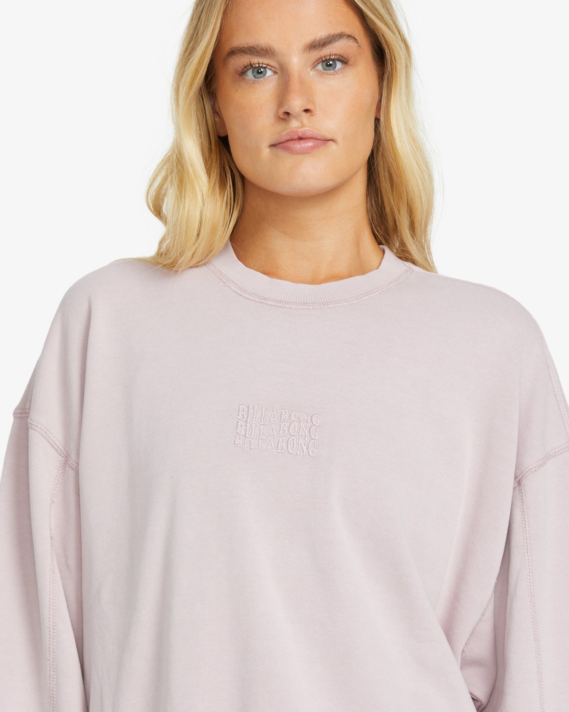 Person wearing a light pink billabong sweatshirt with text on a white background