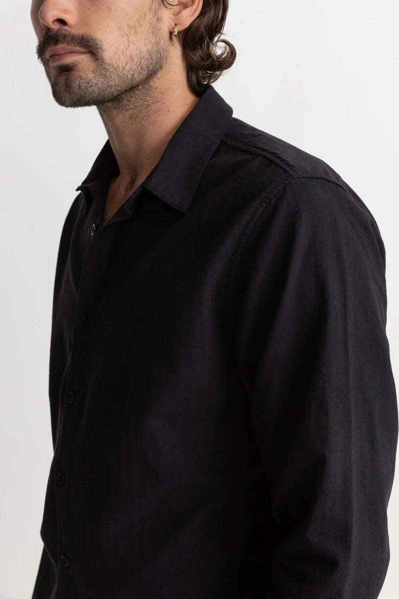 Close up of a man wearing a black rhythim classic linen shirt