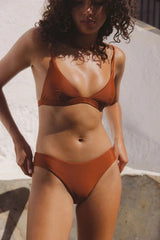 Woman wearing a rhythm classic brown bikini against a white wall.
