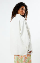 Woman wearing a rhythm camilla oversized white jacket with a floral skirt on a white background