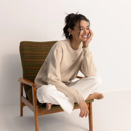 Woman sitting on a wooden chair with a woven backrest against a white background