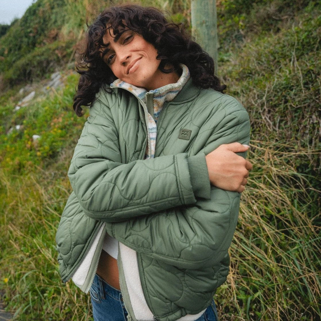 Person wearing a green quilted jacket outdoors in a natural setting
