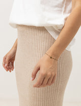 close up of a woman wearing rhythm t-shirt and hayman knit midi skirt against a white background