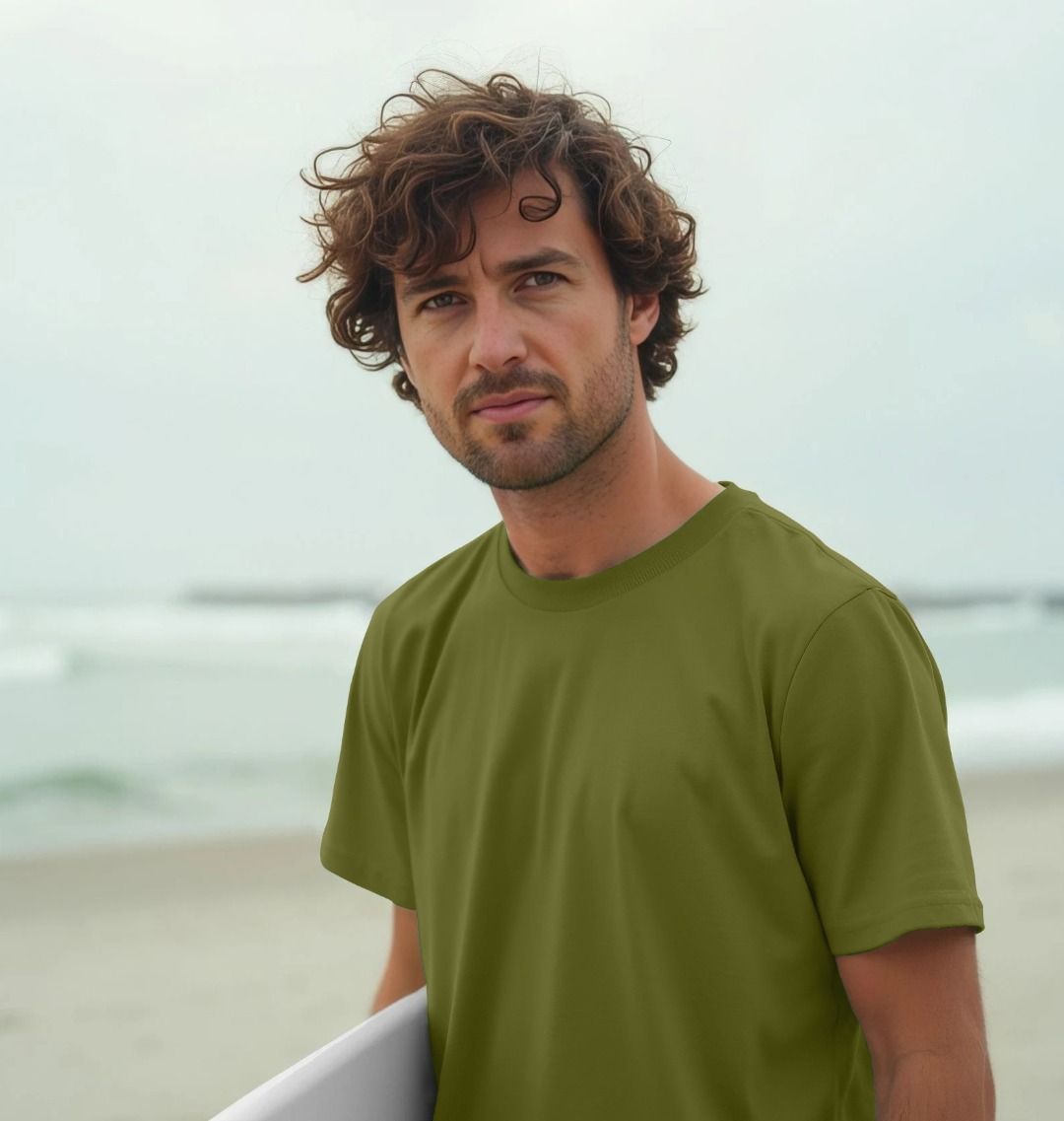 Man with curly hair wearing a green t-shirt on a beach