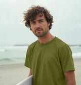 Man with curly hair wearing a green t-shirt on a beach